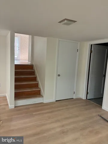 a view of an empty room with wooden floor and stairs