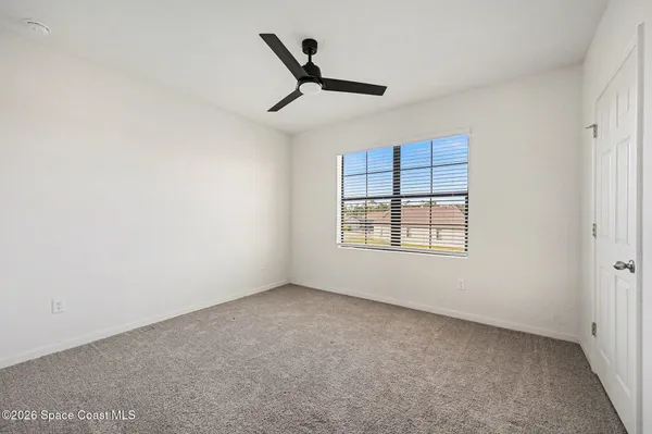 an empty room with windows and ceiling fan view