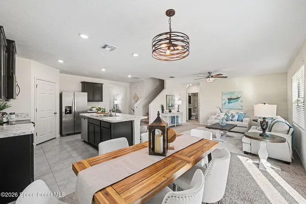 a living room with furniture kitchen view and a chandelier