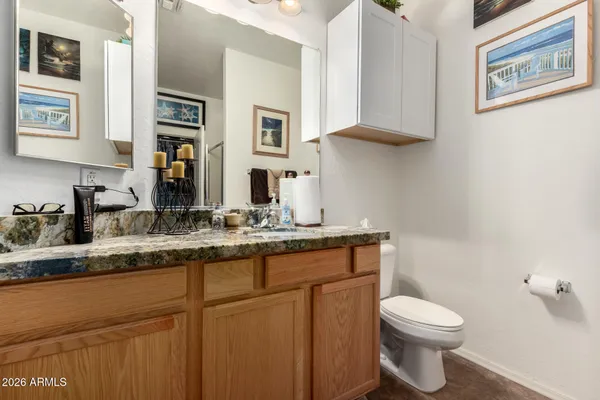 a bathroom with a granite countertop toilet sink and mirror