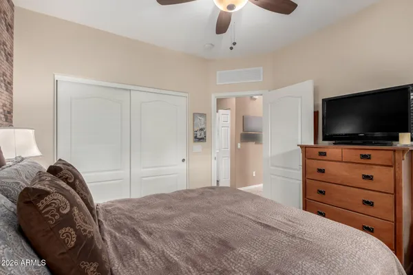 a bedroom with a bed and a flat tv screen on dresser