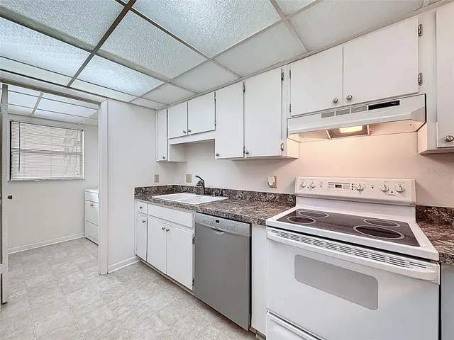 a kitchen with granite countertop white cabinets and white appliances