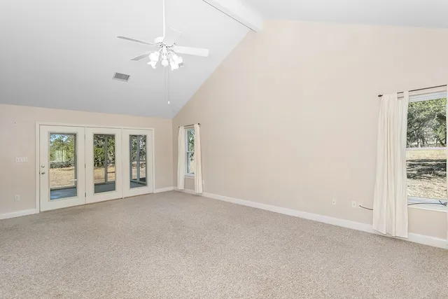 an empty room with windows and chandelier fan