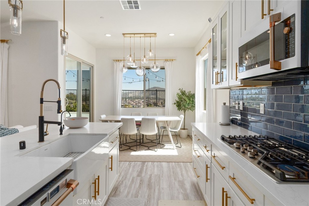 2308 Nova Way Corona, CA 92883 - Photo 12 of 32 a large kitchen with stainless steel appliances a stove a sink dishwasher a dining table and chair with wooden floor