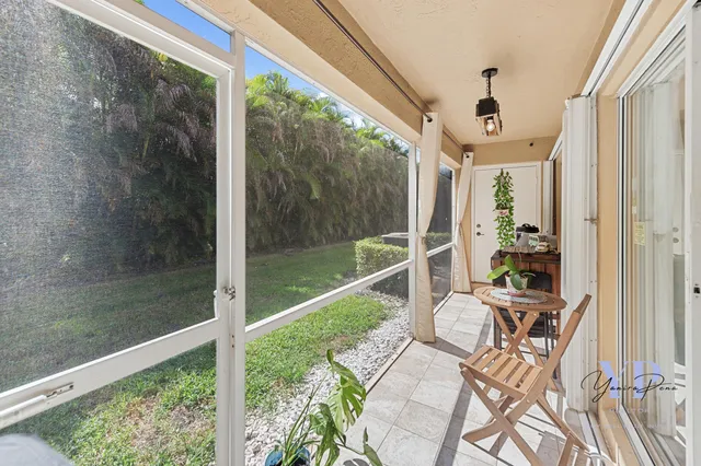 a view of a balcony with a dining table chairs and floor to ceiling window