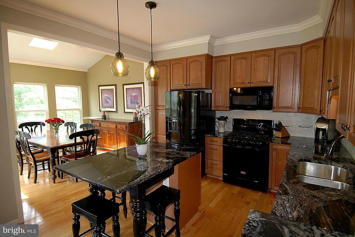 43233 Stillforest Terrace Ashburn, VA 20147 - Photo 11 of 30 a kitchen with a refrigerator a stove a dining table and chairs