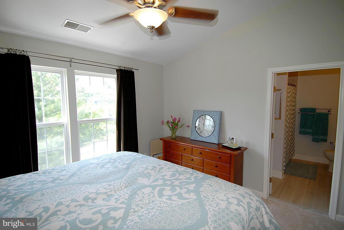 43233 Stillforest Terrace Ashburn, VA 20147 - Photo 17 of 30 a bedroom with a bed and a dresser with mirror