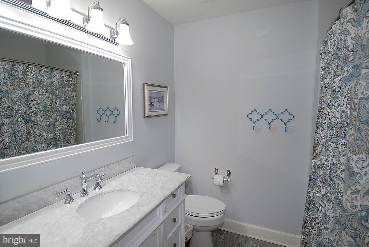 43233 Stillforest Terrace Ashburn, VA 20147 - Photo 23 of 30 a bathroom with a granite countertop sink a mirror and a toilet