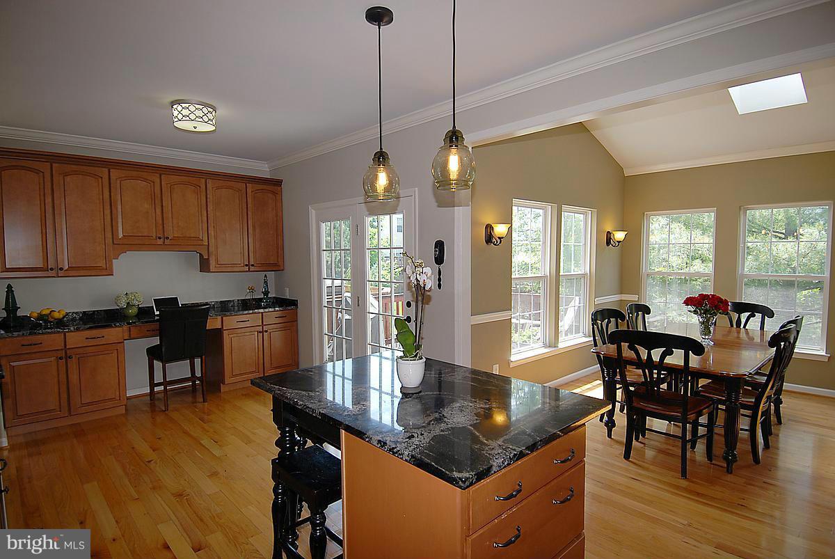 43233 Stillforest Terrace Ashburn, VA 20147 - Photo 9 of 30 a kitchen with stainless steel appliances granite countertop a stove a refrigerator a sink a dining table and chairs with wooden floor