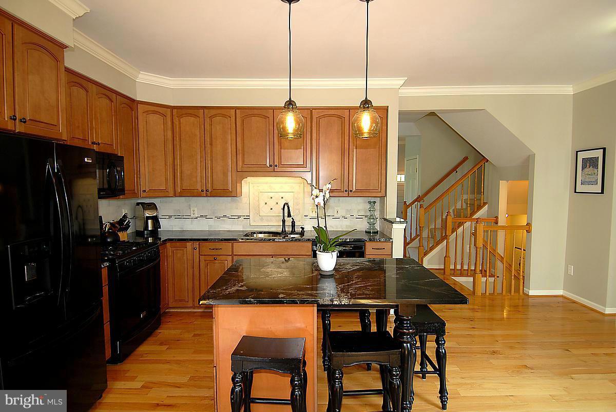 43233 Stillforest Terrace Ashburn, VA 20147 - Photo 10 of 30 a kitchen with granite countertop a table chairs stove a sink and dishwasher