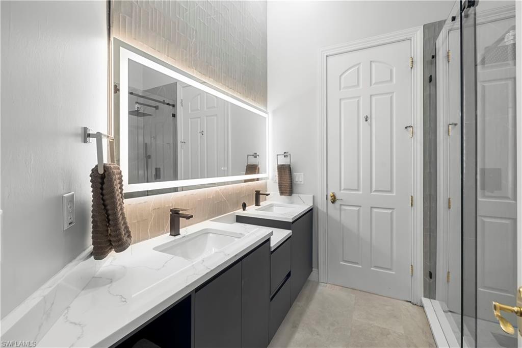 480 Terracina Way Naples, FL 34119 - Photo 22 of 40 Full bath with a shower stall, double vanity, and decorative backsplash