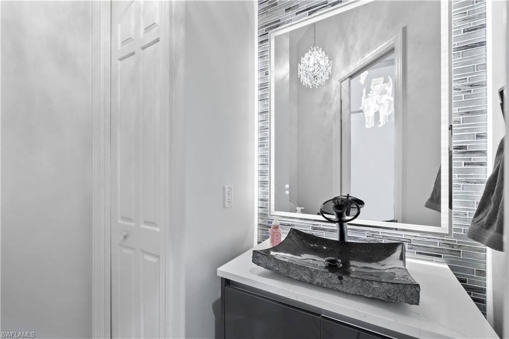 480 Terracina Way Naples, FL 34119 - Photo 24 of 40 Bathroom featuring decorative backsplash, vanity, and a chandelier