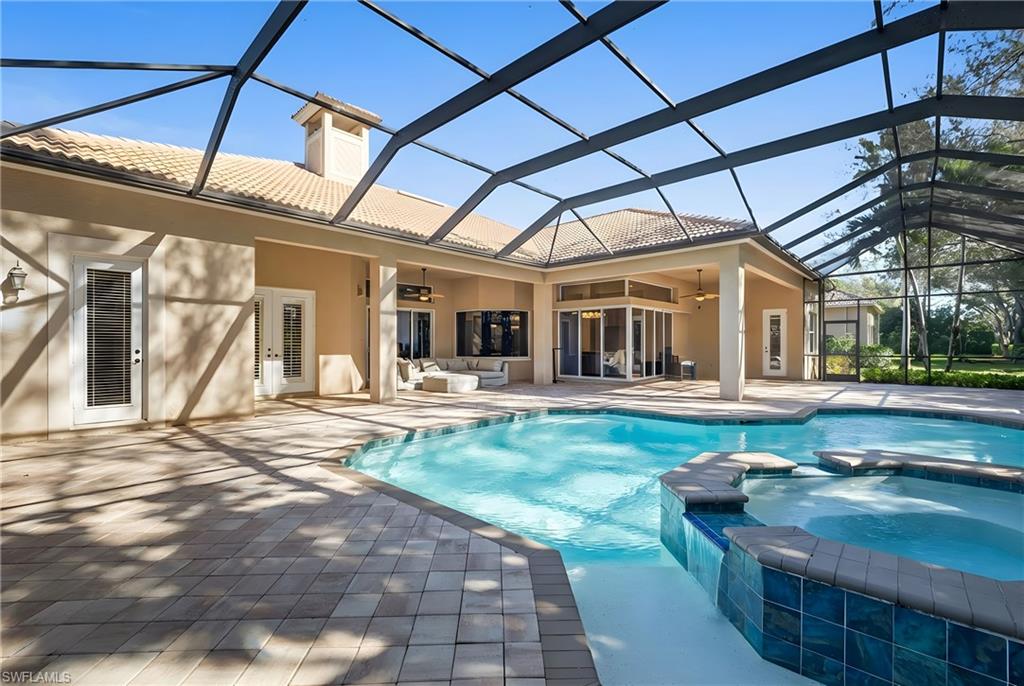 480 Terracina Way Naples, FL 34119 - Photo 29 of 40 View of pool featuring a sunroom, a pool with connected hot tub, glass enclosure, and a patio area