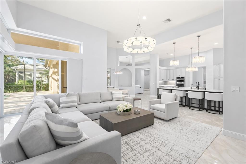 480 Terracina Way Naples, FL 34119 - Photo 9 of 40 Living room with a high ceiling, recessed lighting, arched walkways, and a chandelier