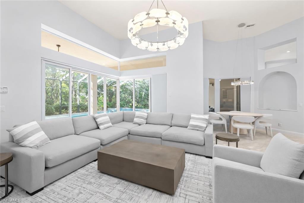 480 Terracina Way Naples, FL 34119 - Photo 10 of 40 Living room with a chandelier and a high ceiling