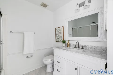 a bathroom with a granite countertop sink vanity mirror and toilet