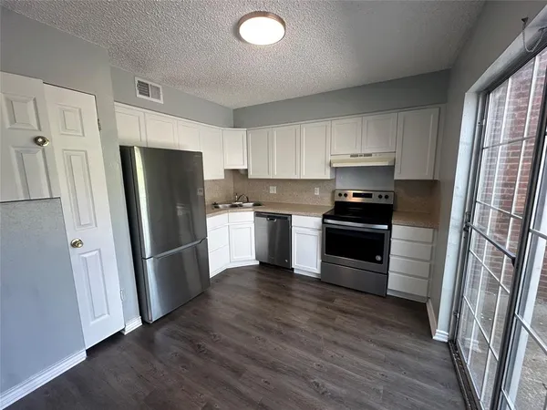 a kitchen with a refrigerator a stove top oven and wooden floor