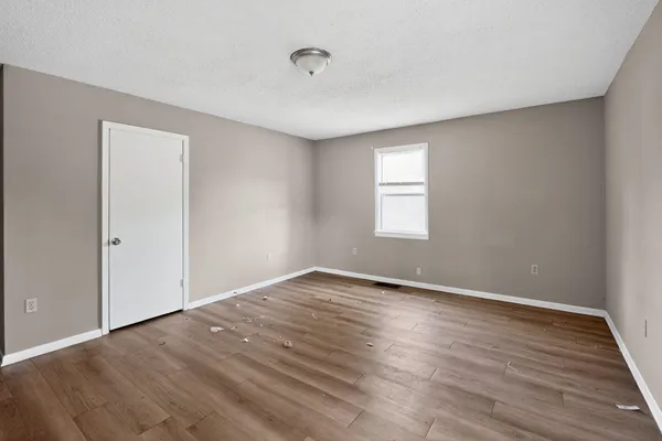 a view of an empty room with wooden floor and window