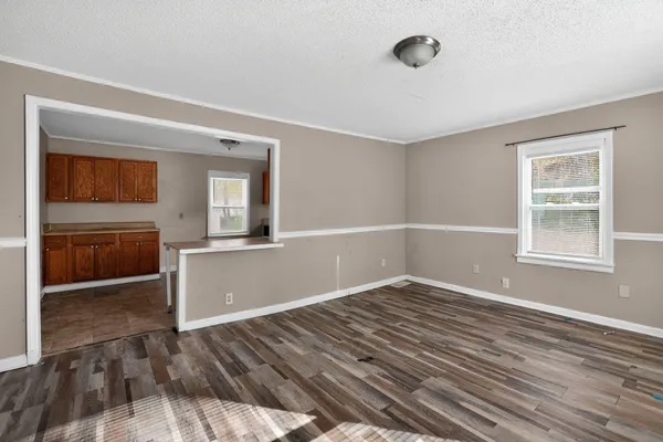 a view of an empty room with window and wooden floor