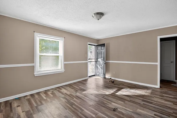a view of an empty room with wooden floor and a window