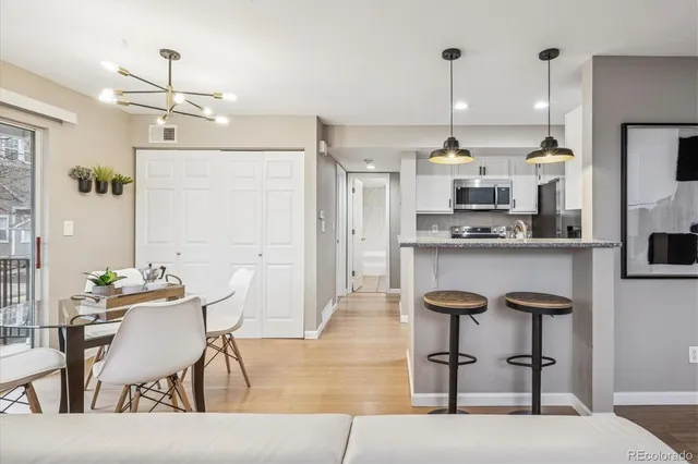 a kitchen with stainless steel appliances kitchen island a table in it and white cabinets
