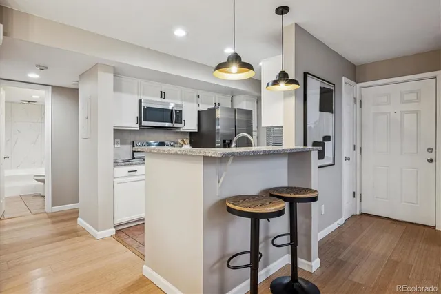 a kitchen with stainless steel appliances a stove a refrigerator and a dining table with wooden floor