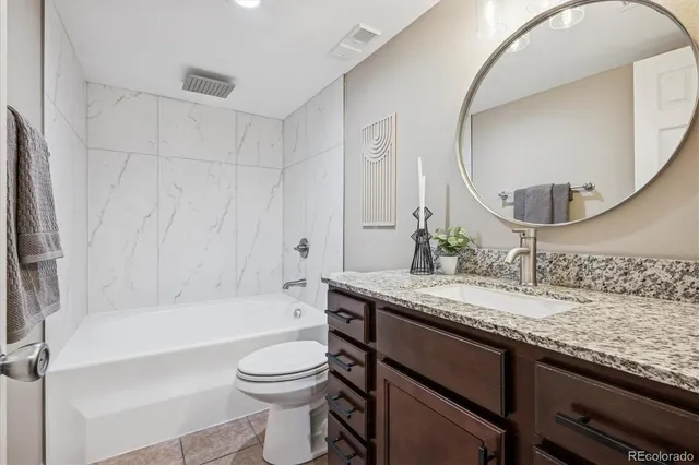 a bathroom with a granite countertop sink a toilet and bathtub
