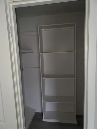 a walk in closet with wooden floor
