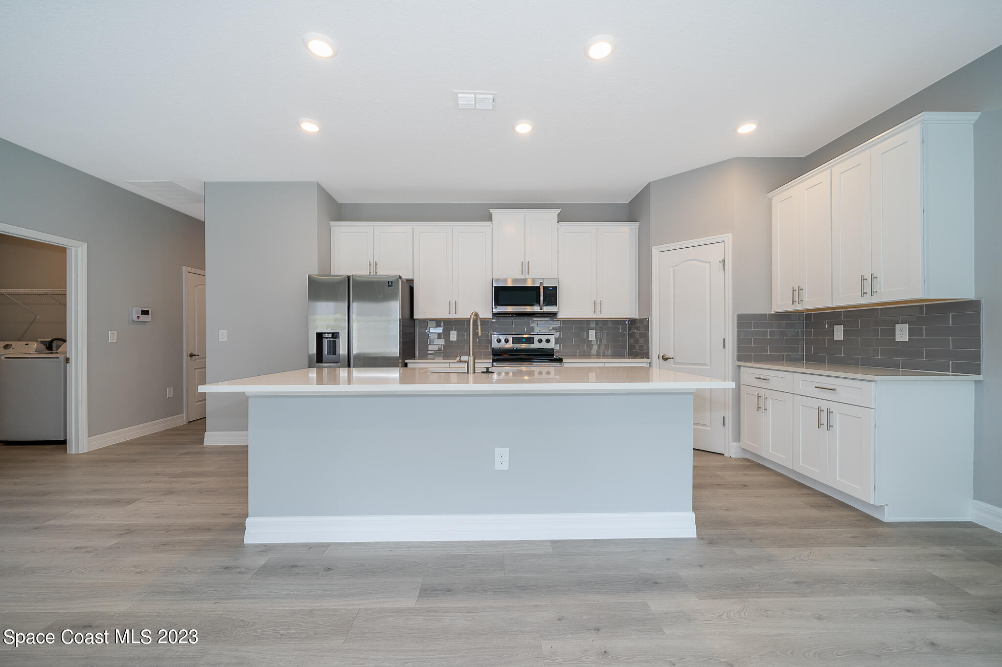 209 Tatum Road Southwest Palm Bay, FL 32908 - Photo 13 of 27 a view living room with stainless steel appliances granite countertop a stove a sink a refrigerator and white cabinets