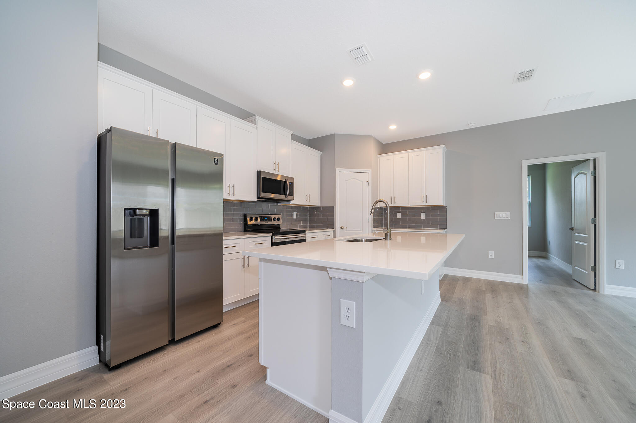 209 Tatum Road Southwest Palm Bay, FL 32908 - Photo 14 of 27 a kitchen with kitchen island a refrigerator sink and wooden floor