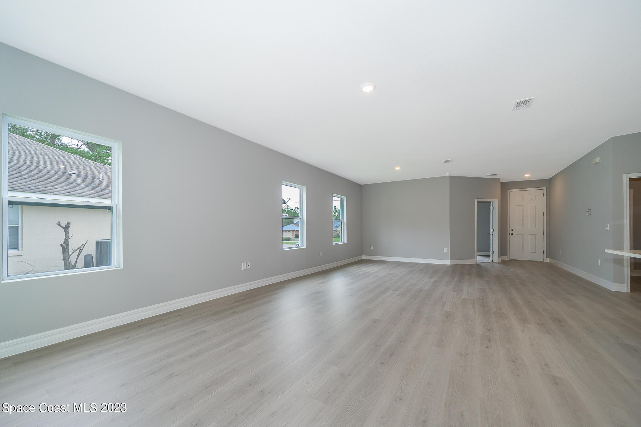 209 Tatum Road Southwest Palm Bay, FL 32908 - Photo 7 of 27 an empty room with wooden floor and windows