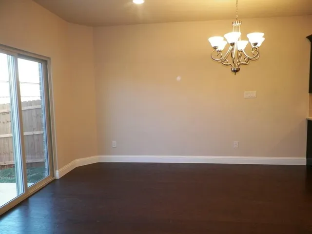 a view of a chandelier in big room with wooden floor and windows