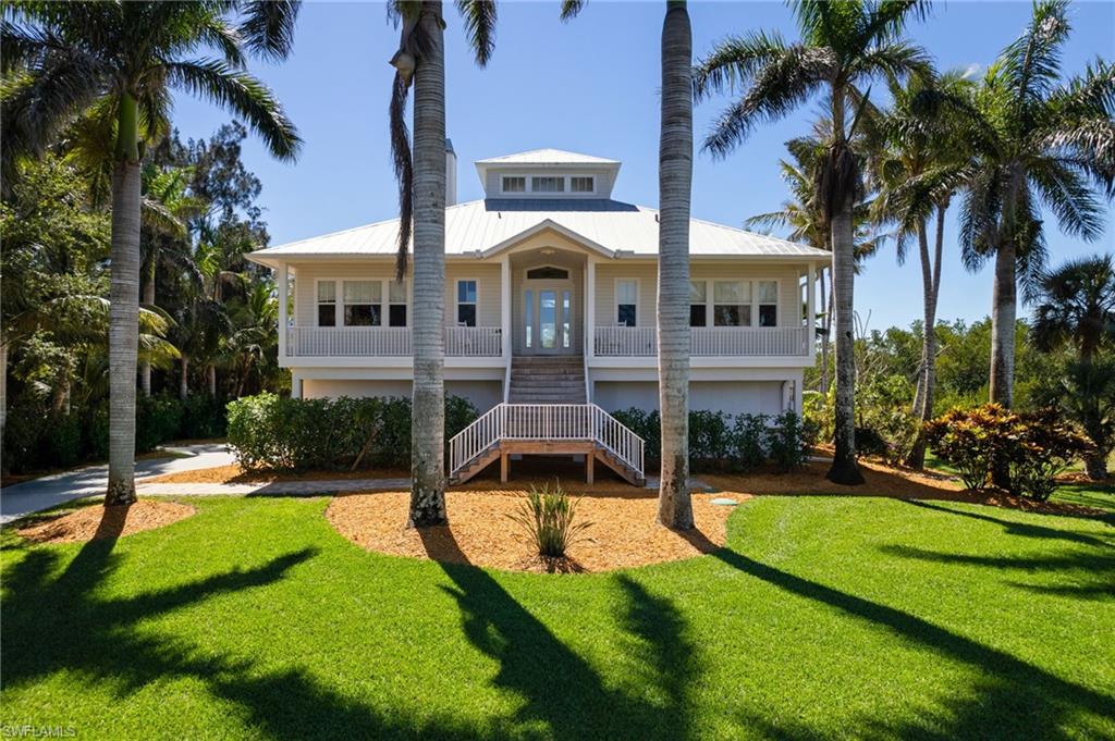 Front of Home with open porch and Royal Palm trees