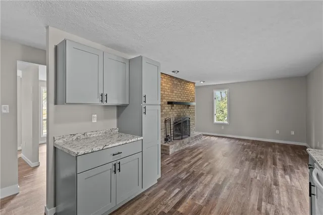 a kitchen with granite countertop a stove top oven a sink dishwasher and a refrigerator with wooden floor