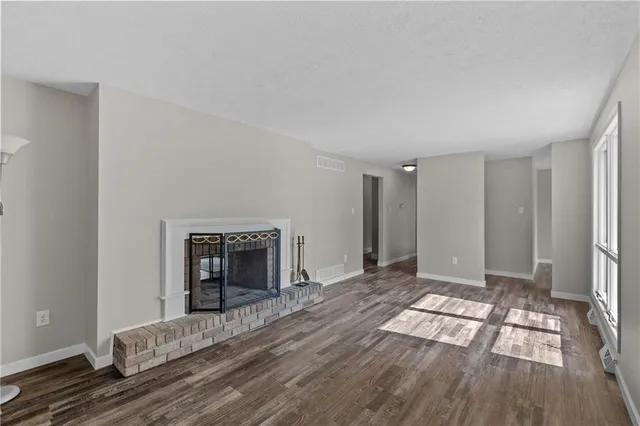 a view of an empty room with wooden floor and a fireplace