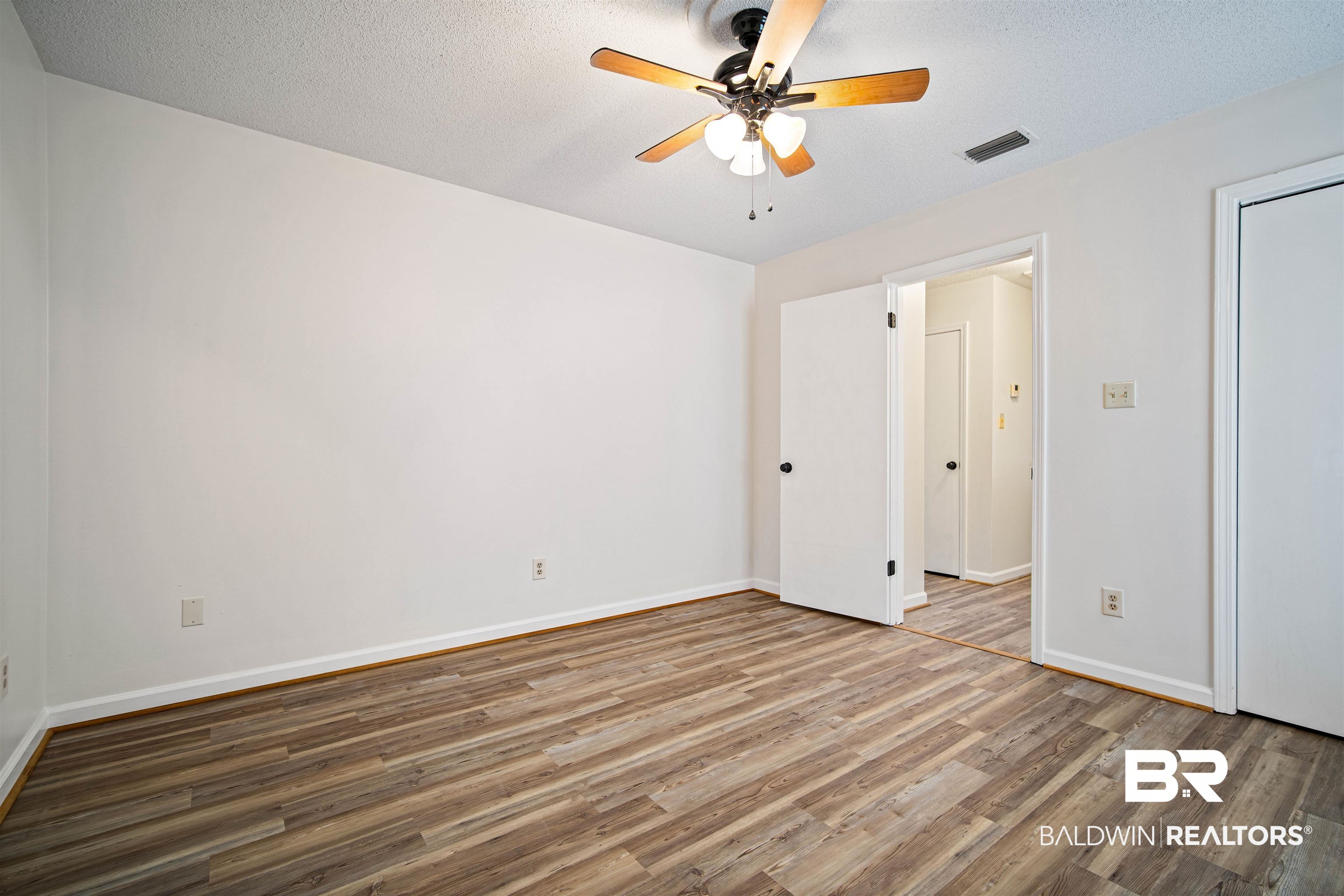 6701 Howells Ferry Road Mobile, AL 36618 - Photo 21 of 25 Unfurnished bedroom featuring ceiling fan, dark hardwood / wood-style flooring, and a textured ceiling