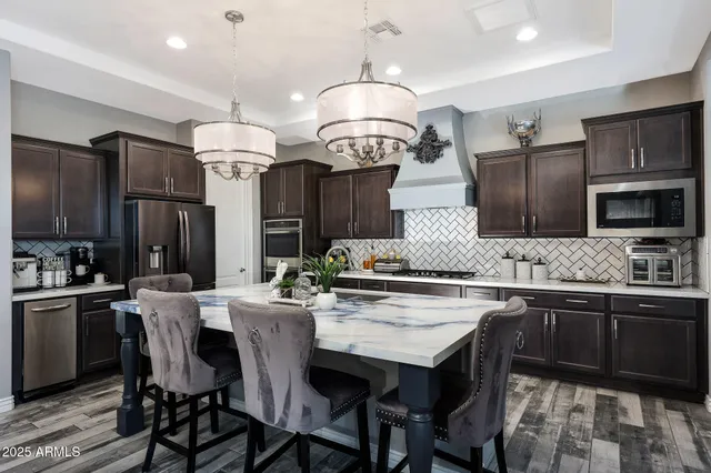 a kitchen with stainless steel appliances a stove a sink island and chairs