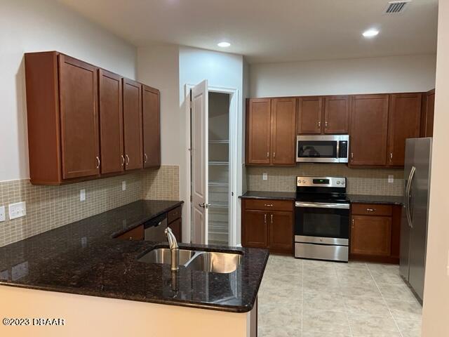 742 Aldenham Lane Ormond Beach, FL 32174 - Photo 6 of 25 a kitchen with granite countertop wooden cabinets a refrigerator and a sink