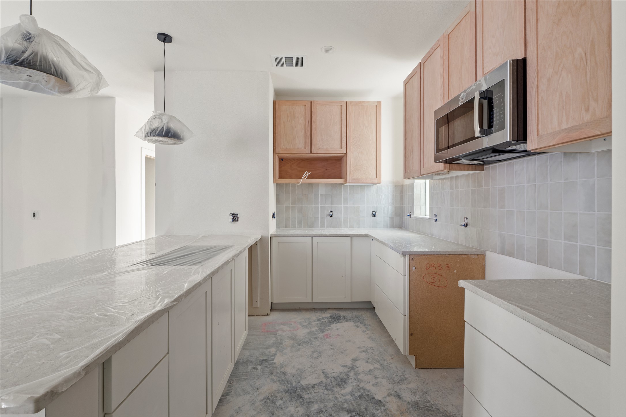 1180 Lott Avenue Austin, TX 78721 - Photo 5 of 40 Kitchen with stainless steel microwave, decorative backsplash, pendant lighting, a peninsula, and light brown cabinets