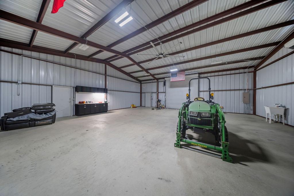 1161 Alsdorf Road Ennis, TX 75119 - Photo 23 of 28 Spacious utility building featuring a concrete floor, high ceilings with exposed metal trusses, corrugated metal walls, and overhead lighting