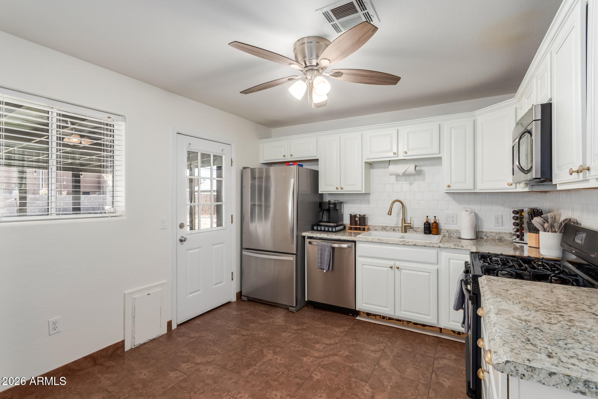2715 West Royal Palm Road Phoenix, AZ 85051 - Photo 14 of 32 a kitchen with stainless steel appliances granite countertop a refrigerator a sink a stove and white cabinets