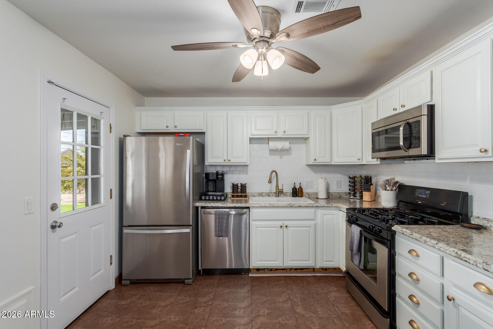 2715 West Royal Palm Road Phoenix, AZ 85051 - Photo 18 of 32 a kitchen with a refrigerator a sink stainless steel appliances cabinets and a window