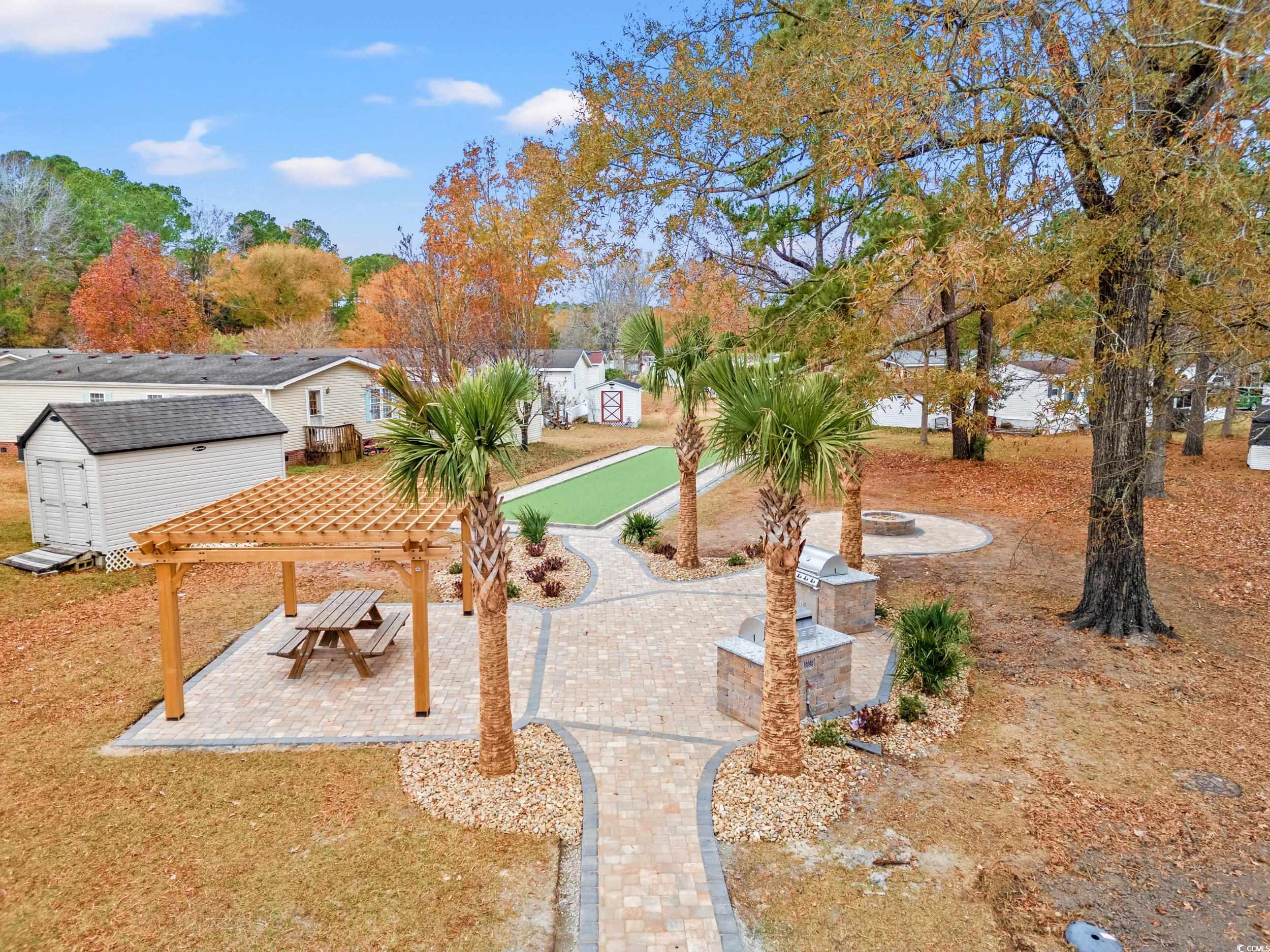 467 Freedom Circle Myrtle Beach, SC 29588 - Photo 36 of 38 View of grassy yard featuring a storage unit, a pergola, a patio area, and an outdoor fire pit