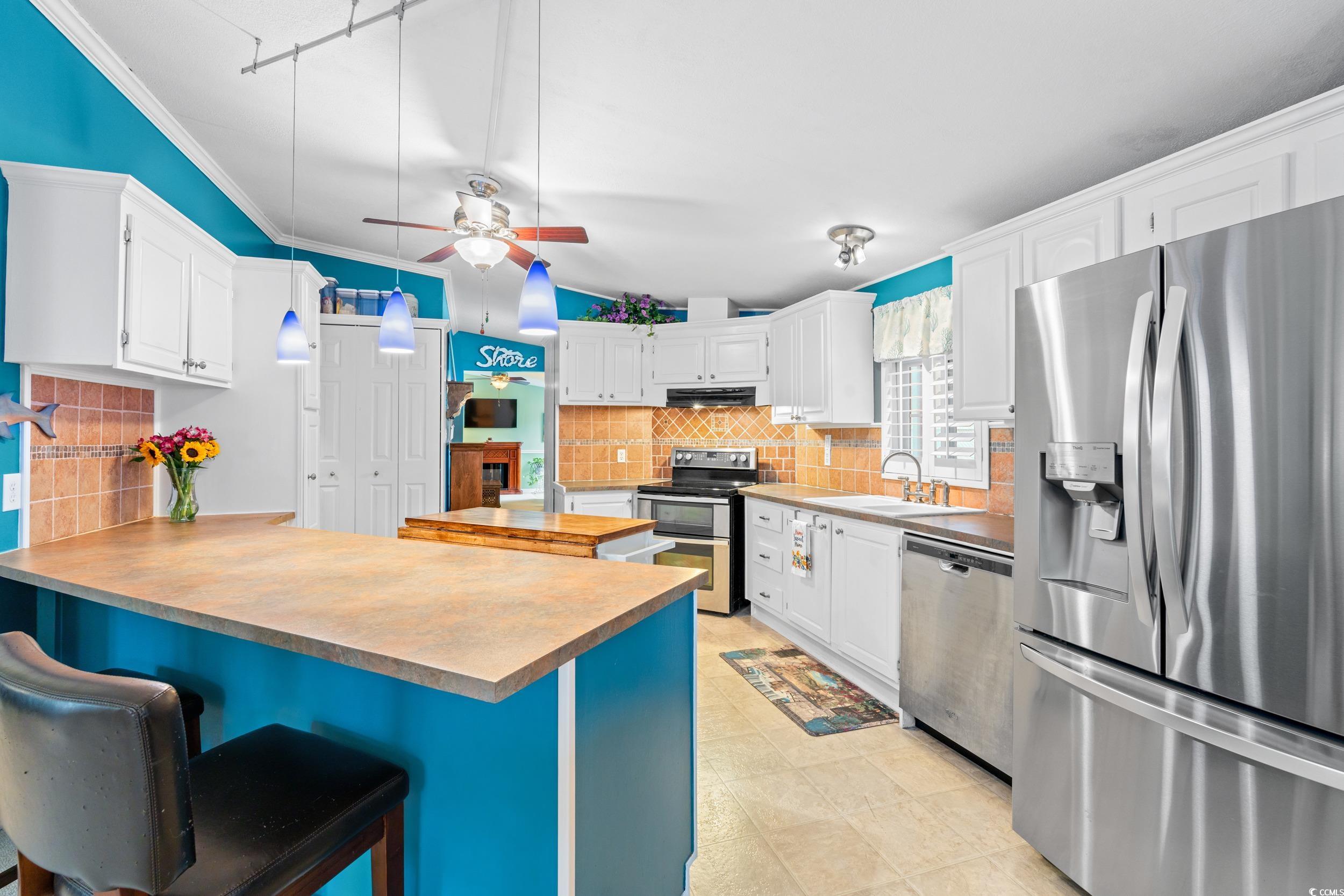 467 Freedom Circle Myrtle Beach, SC 29588 - Photo 10 of 38 Kitchen with stainless steel appliances, a peninsula, a kitchen breakfast bar, white cabinets, and crown molding