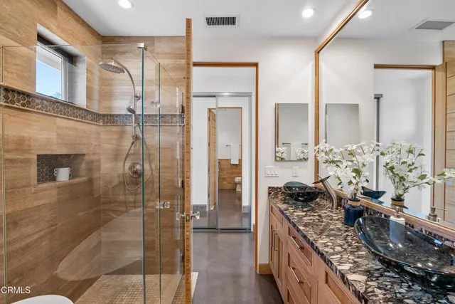 a bathroom with a granite countertop shower a mirror and a shower