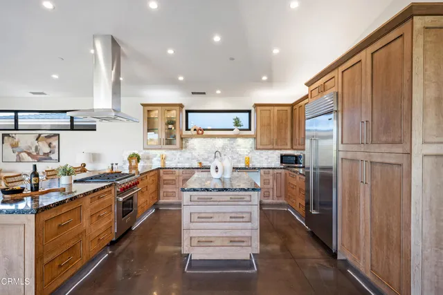 a kitchen with stainless steel appliances kitchen island granite countertop a refrigerator and a stove top oven