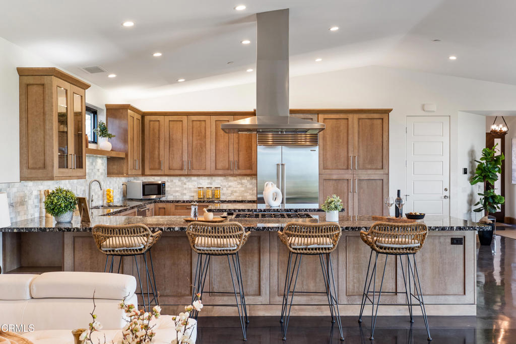 5572 Rainier Street Ventura, CA 93003 - Photo 6 of 29 a kitchen with stainless steel appliances granite countertop a stove top oven a sink a dining table and chairs