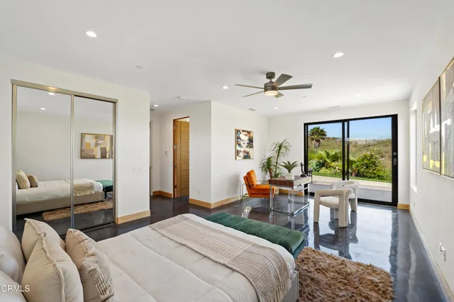 a bedroom with furniture a ceiling fan and a large window