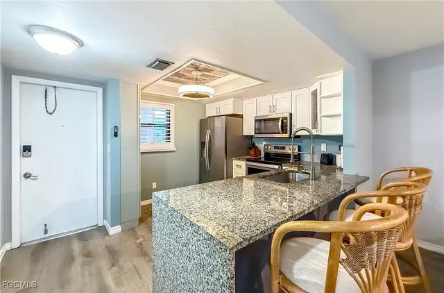 a kitchen with granite countertop kitchen island stainless steel appliances a stove refrigerator sink and microwave