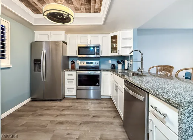 a kitchen with stainless steel appliances granite countertop a refrigerator a stove a sink and a microwave